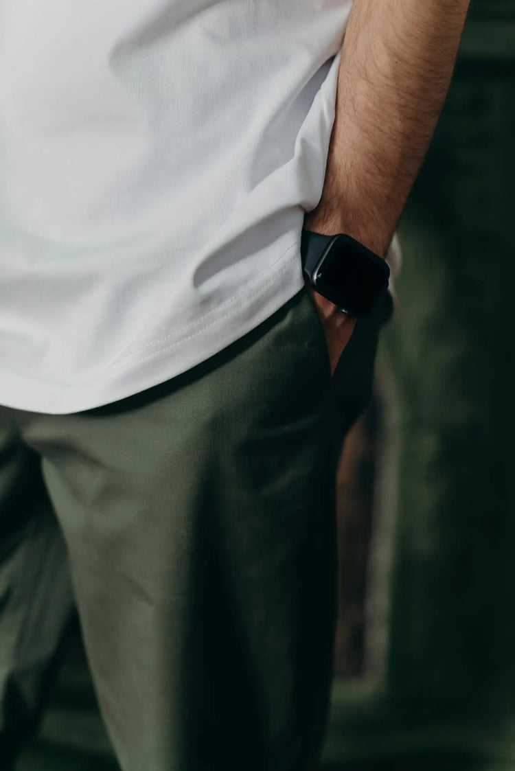 Black smartwatch on wrist with white shirt sleeve in Men’s Bottoms collection.