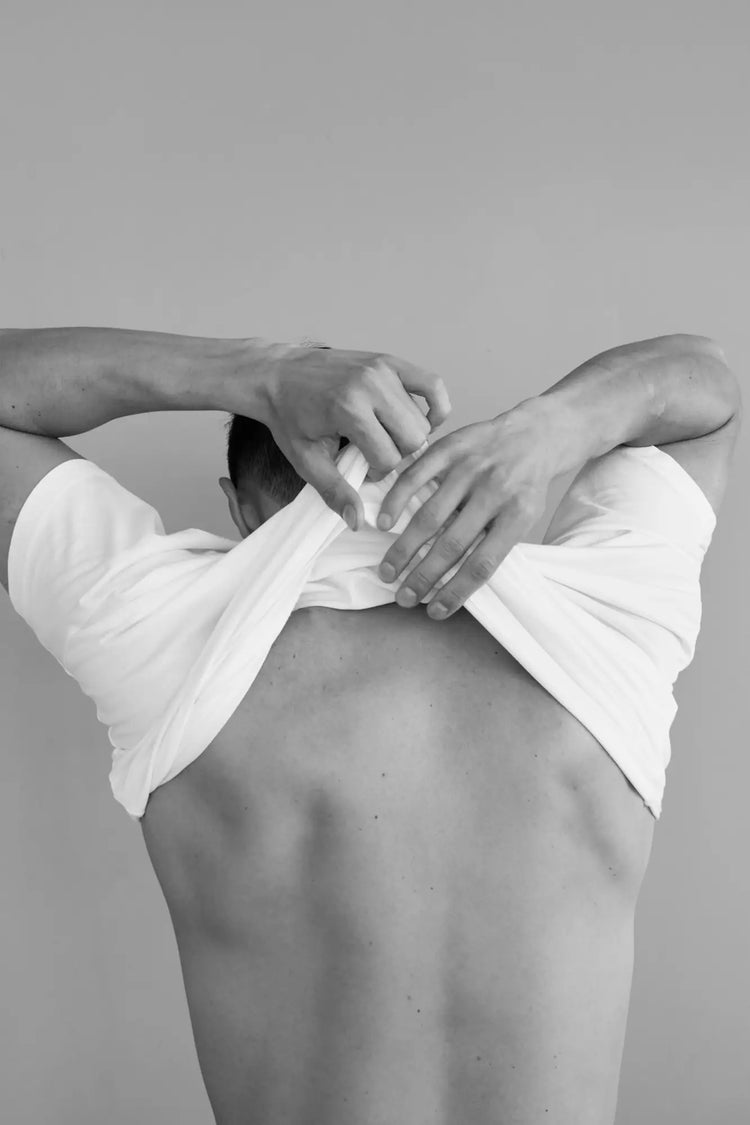 Hands stretching a white garment from the Men’s Tops collection.