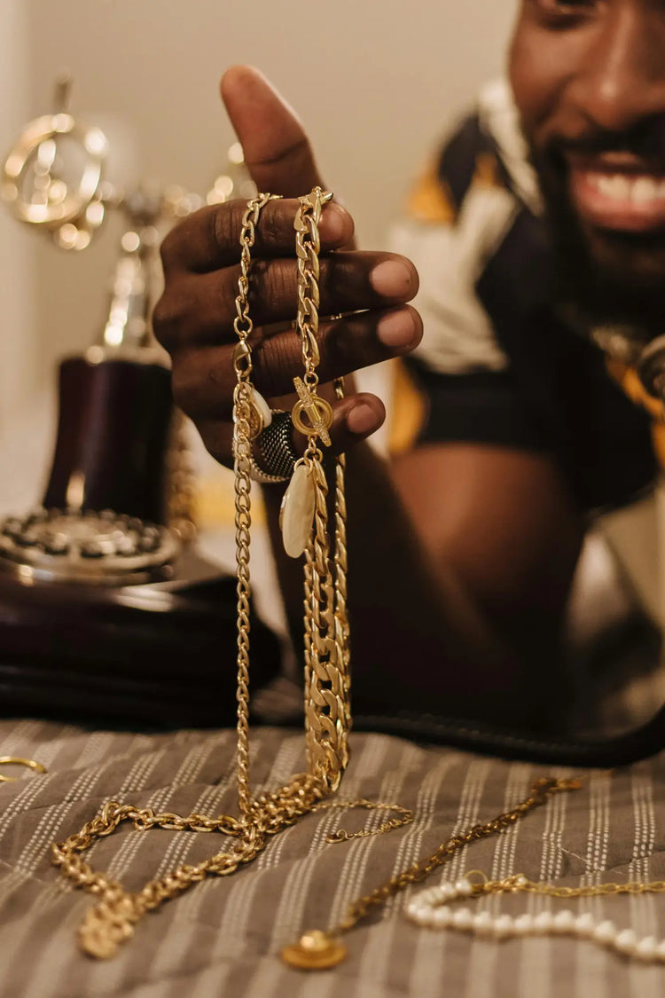 Gold chain necklace held between fingers in Necklaces & Pendants collection