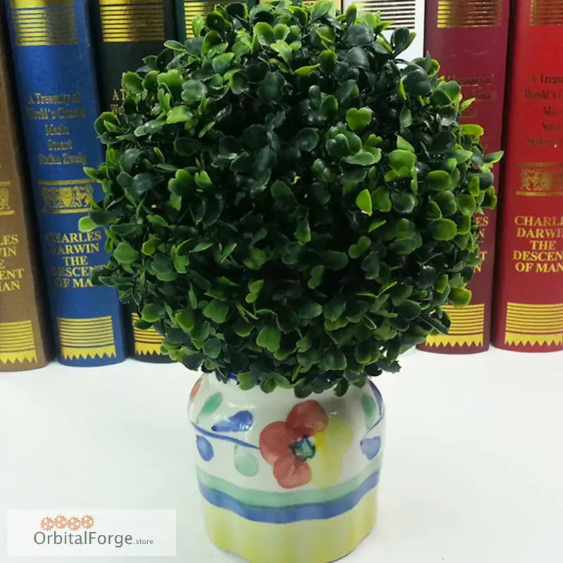 Artificial boxwood topiary ball in a floral-painted ceramic pot.