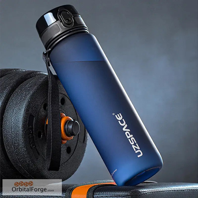 Navy blue sports water bottle with a black lid leaning against exercise weights.