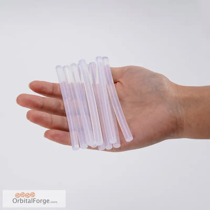 Clear plastic drinking straws in hand with Transparent Hot Glue Sticks for crafts